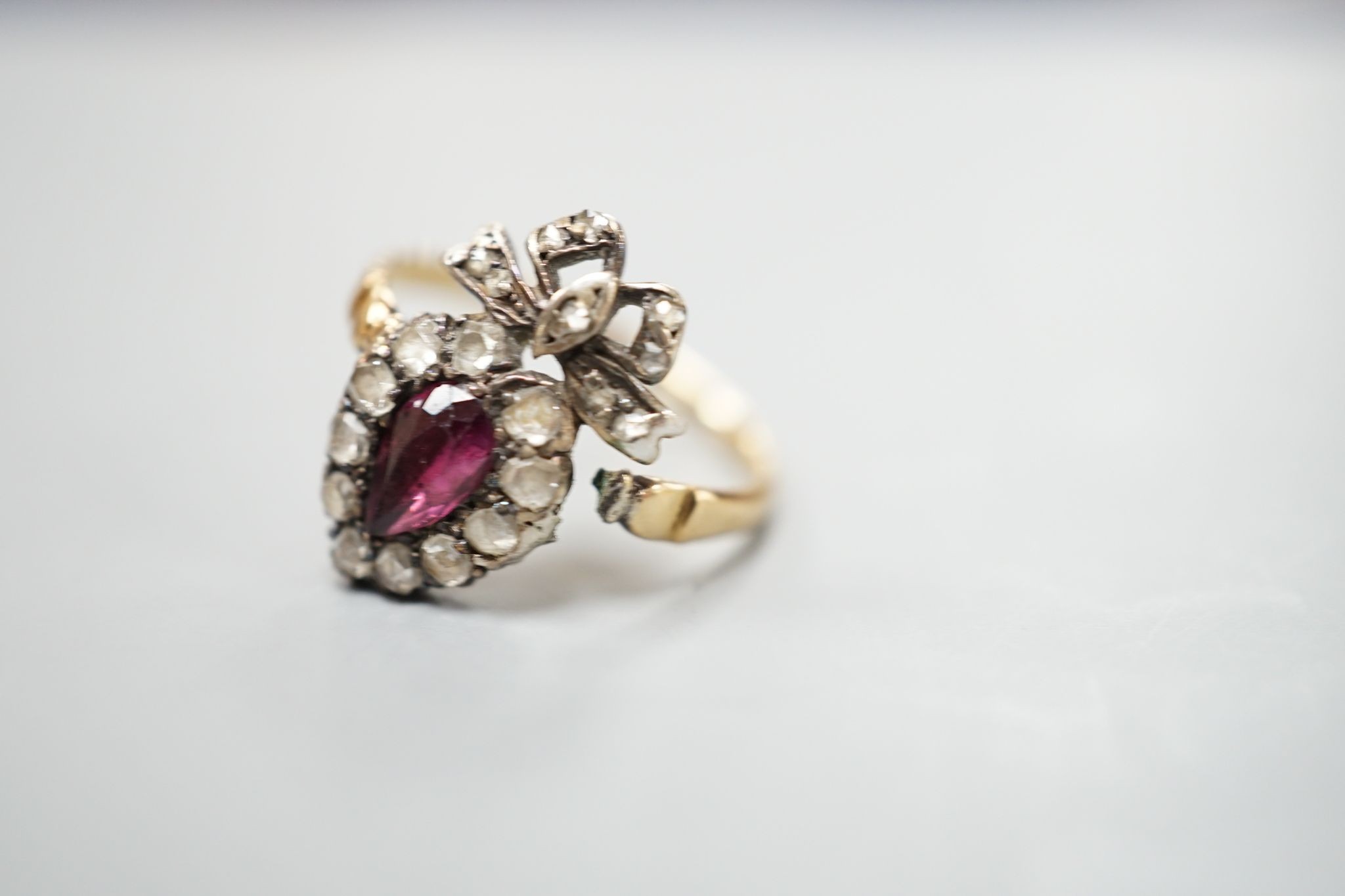 A 19th century yellow metal, garnet and rose cut diamond set heart shaped ring, with ribbon bow crest (shank broken), approx. size H, gross weight 2.2 grams.